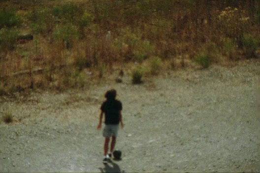 a young boy riding a skateboard down a dirt road