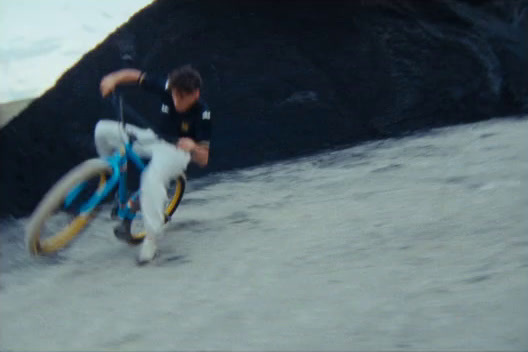 a man riding a bike down a sandy beach