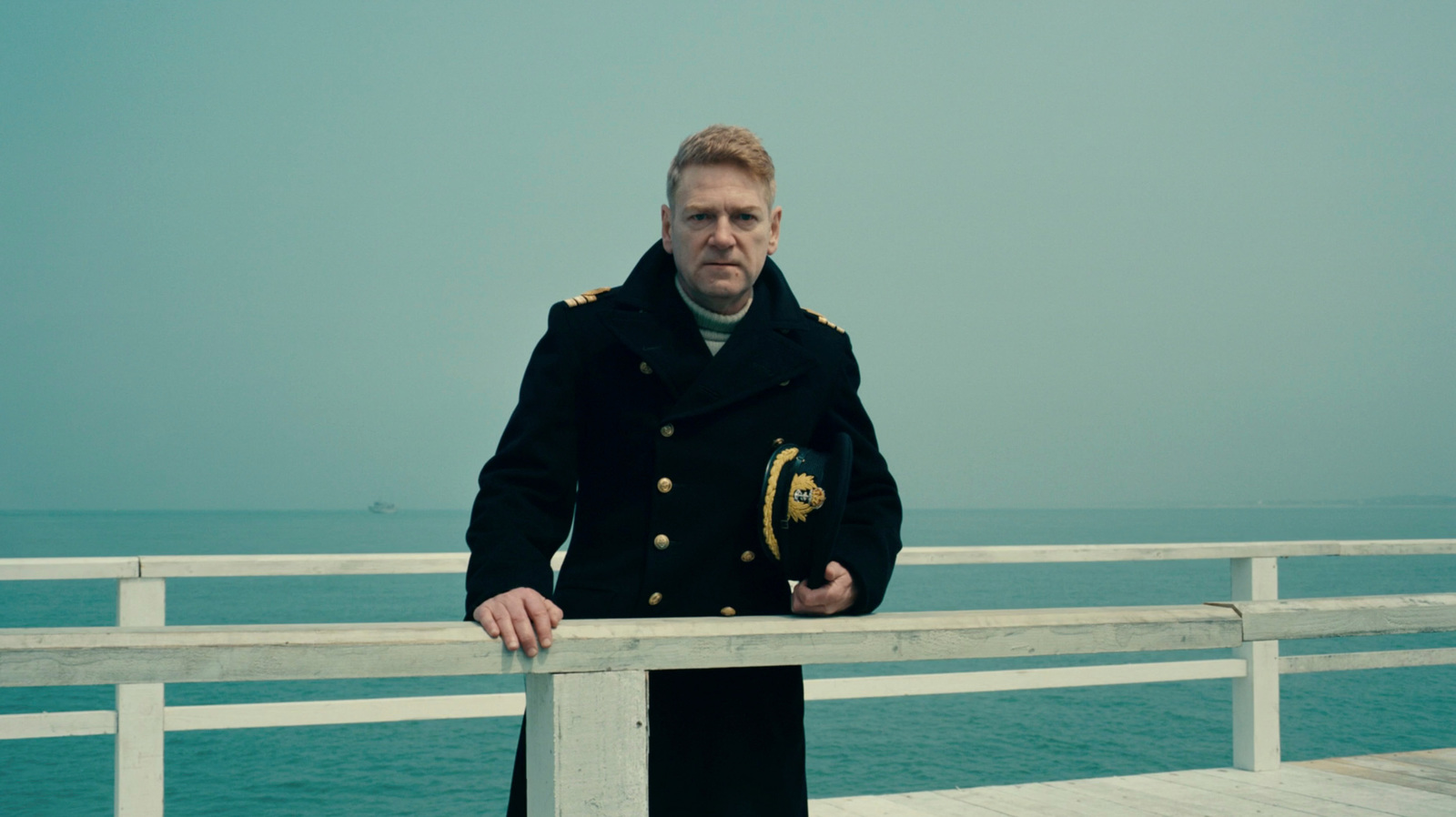 a man standing on a pier next to the ocean