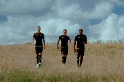 a group of men walking across a grass covered field