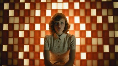 a woman sitting in front of a wall with squares on it