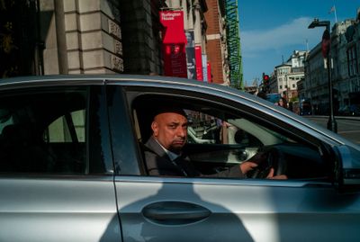 a man sitting in a silver car on a city street