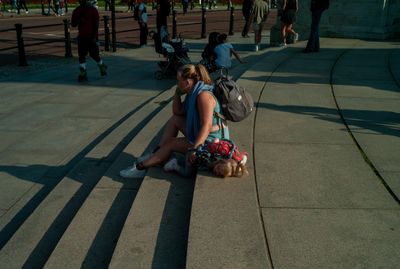 a couple of people sitting on a sidewalk next to each other