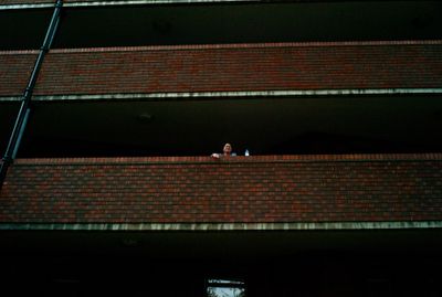 a woman standing on a balcony next to a brick building