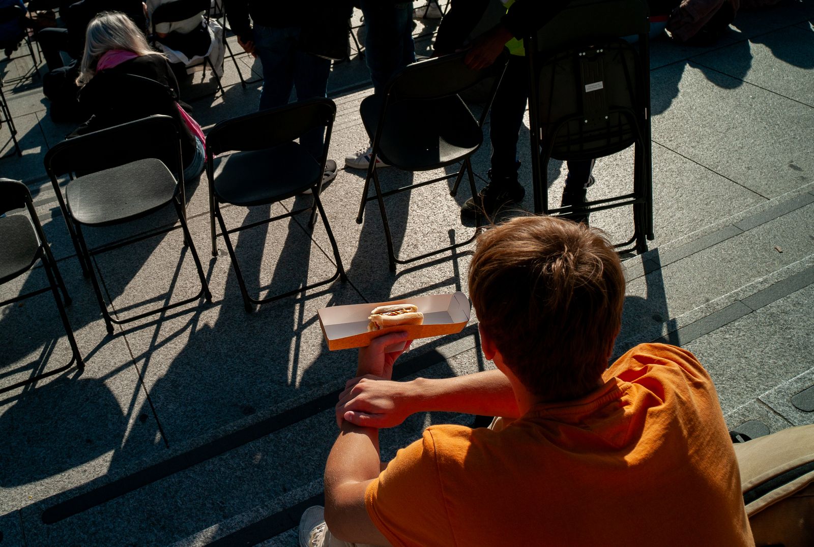 a young boy sitting in a chair holding a hot dog