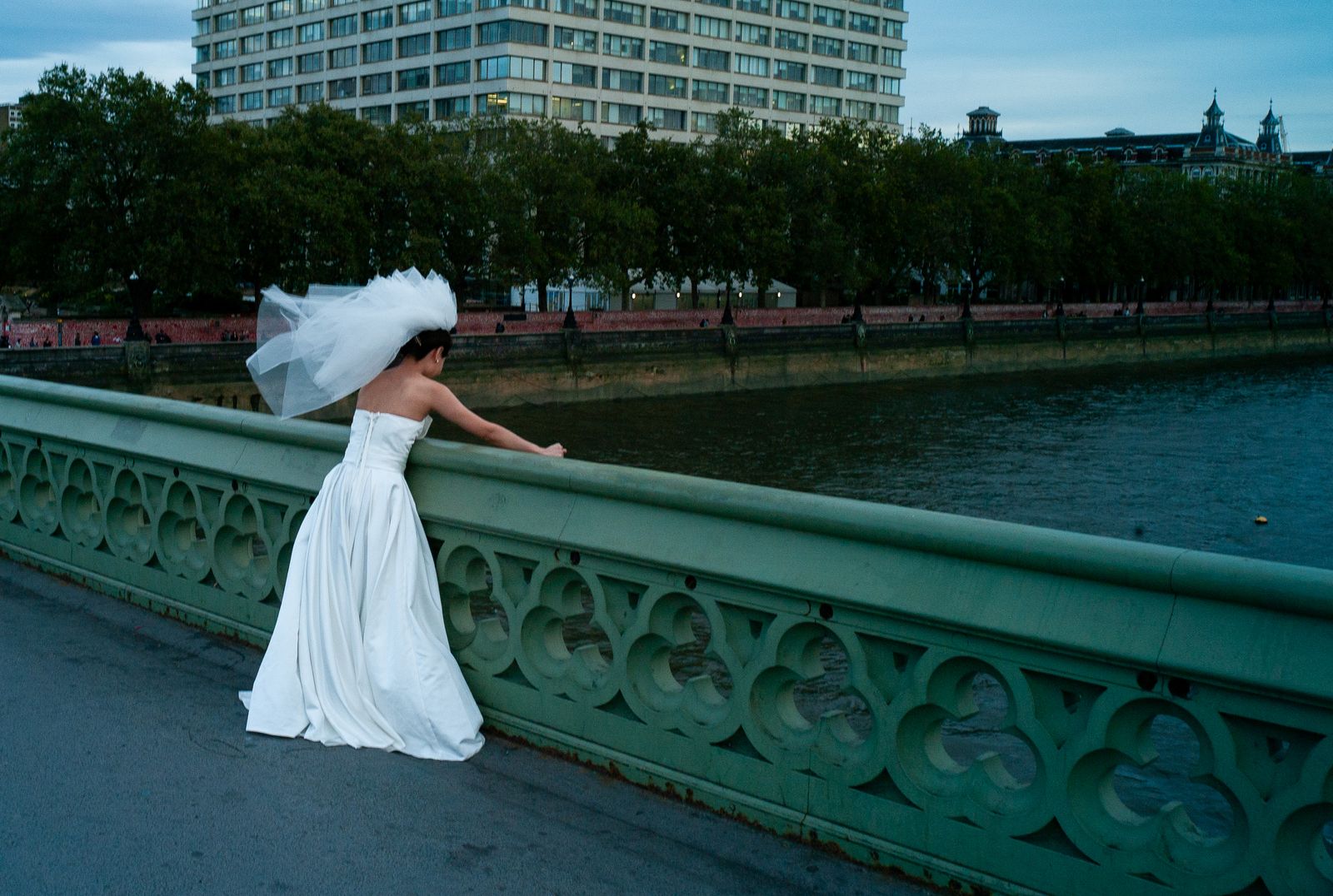 a woman in a white dress is standing on a bridge