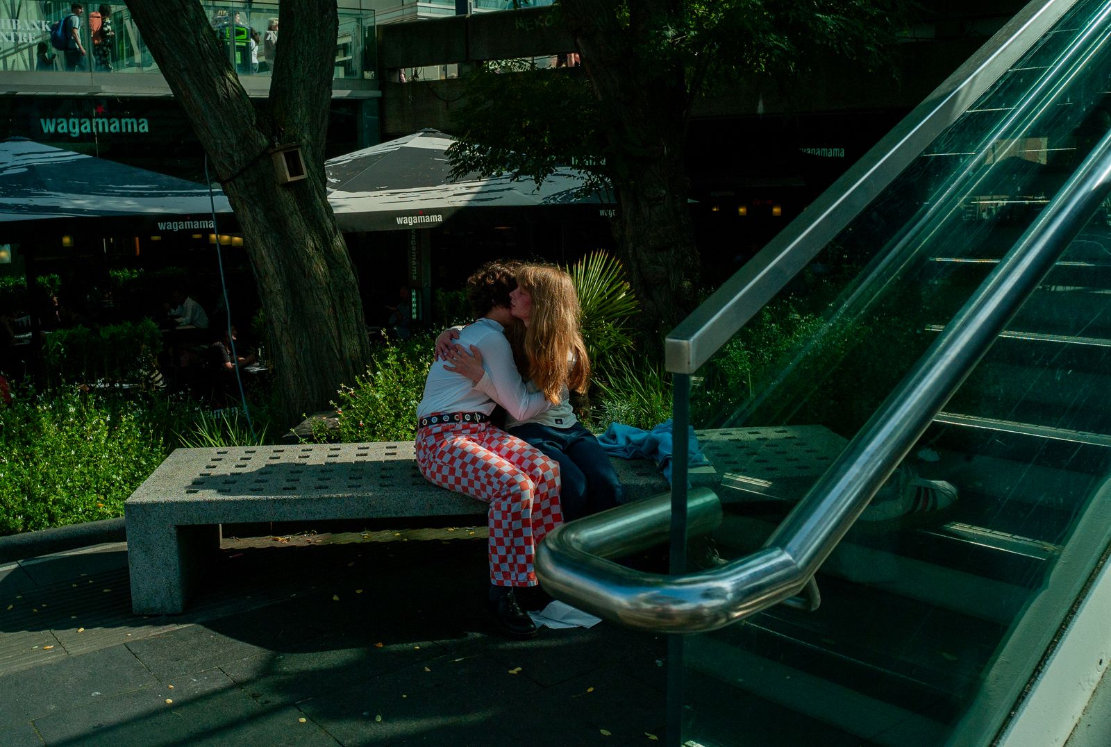 a woman sitting on a bench next to an escalator