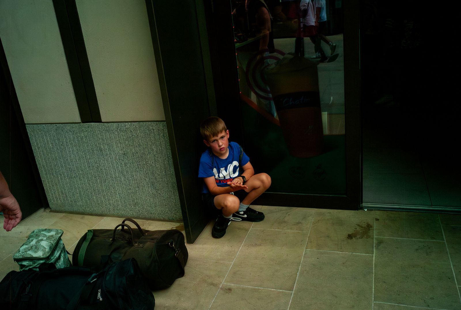 a young boy sitting on the ground next to a pile of luggage