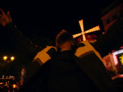 a man standing in front of a cross at night