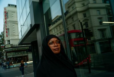 a woman in a black hijab is standing in front of a building