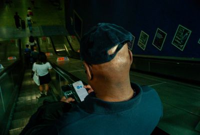 a man standing on an escalator holding a cell phone