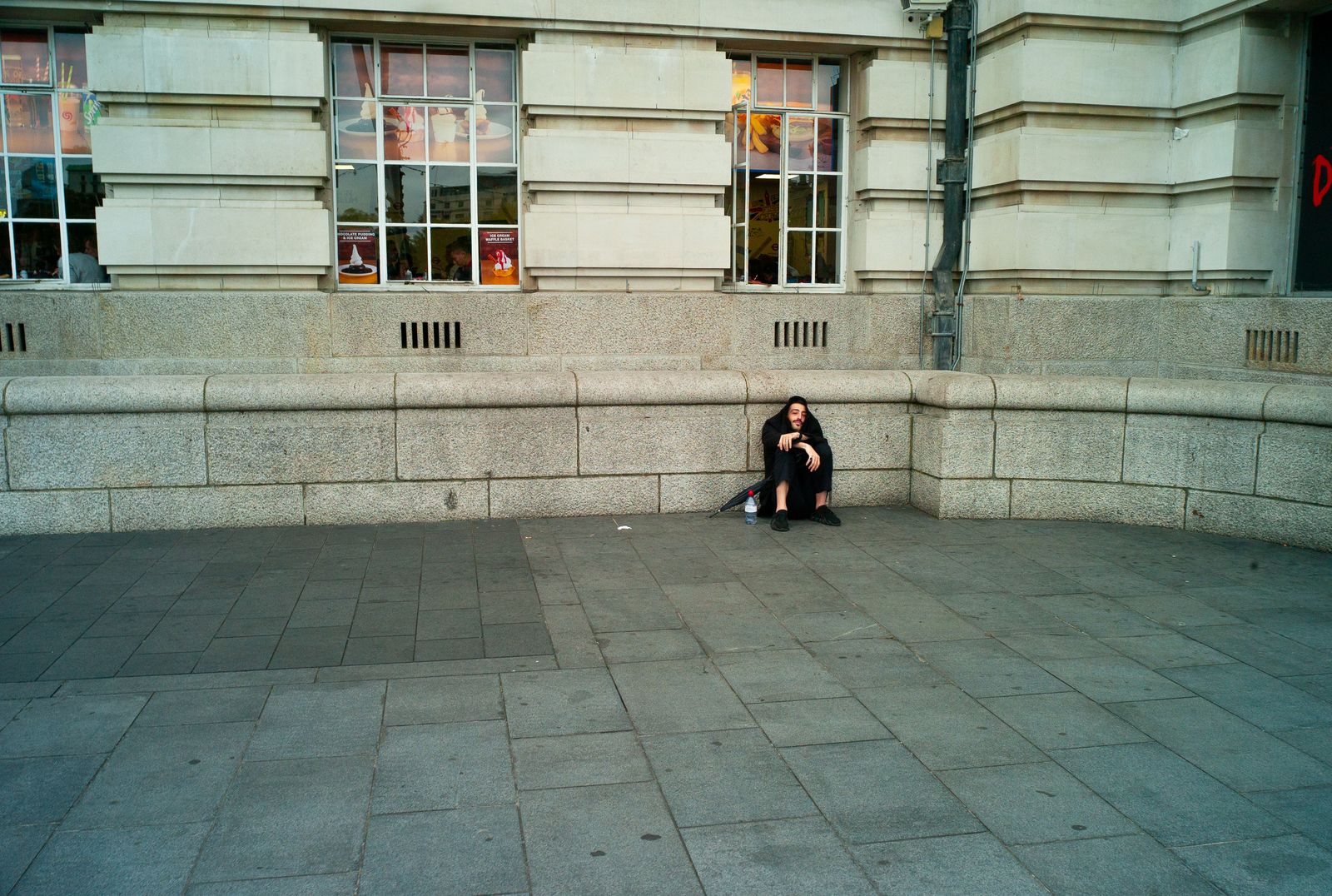 a woman sitting on the ground in front of a building