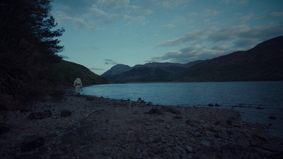 a person standing on a rocky shore next to a body of water