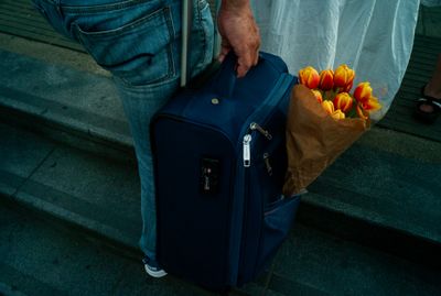 a man holding a bag of tulips and a brown paper bag