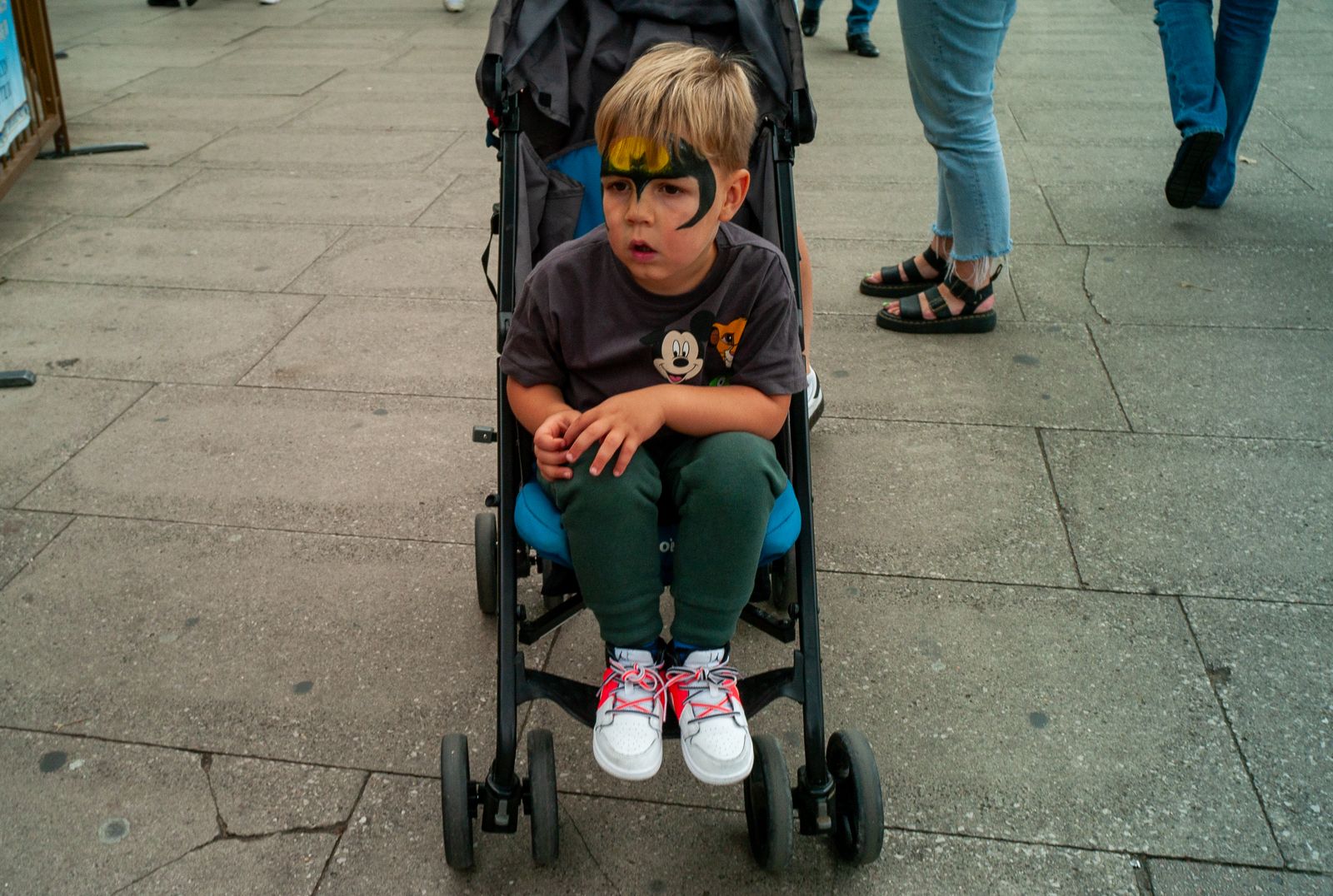 a young boy sitting in a stroller on a sidewalk