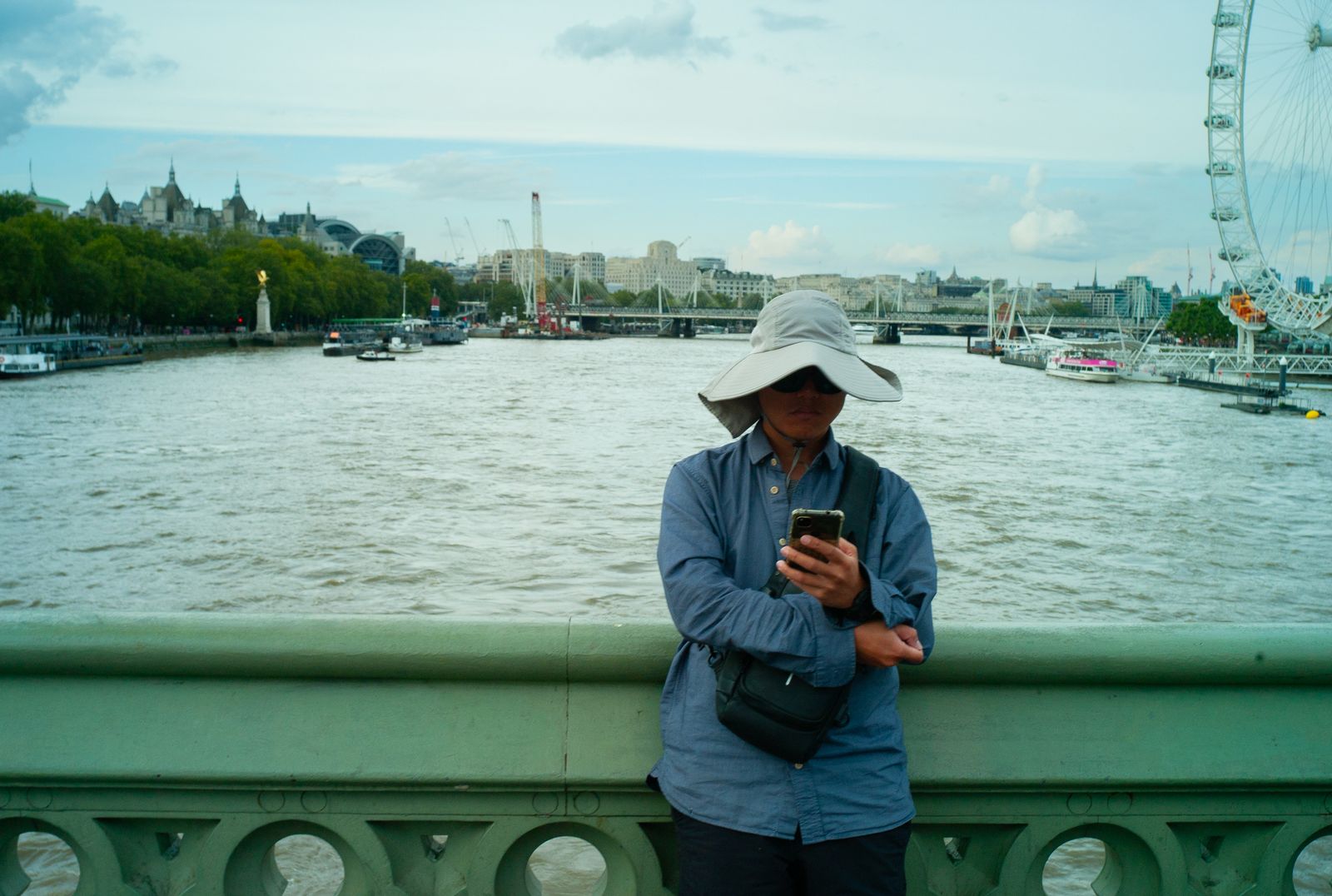 a woman standing on a bridge looking at her cell phone