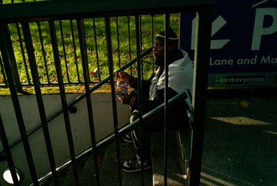 a man sitting on a stair rail holding a teddy bear