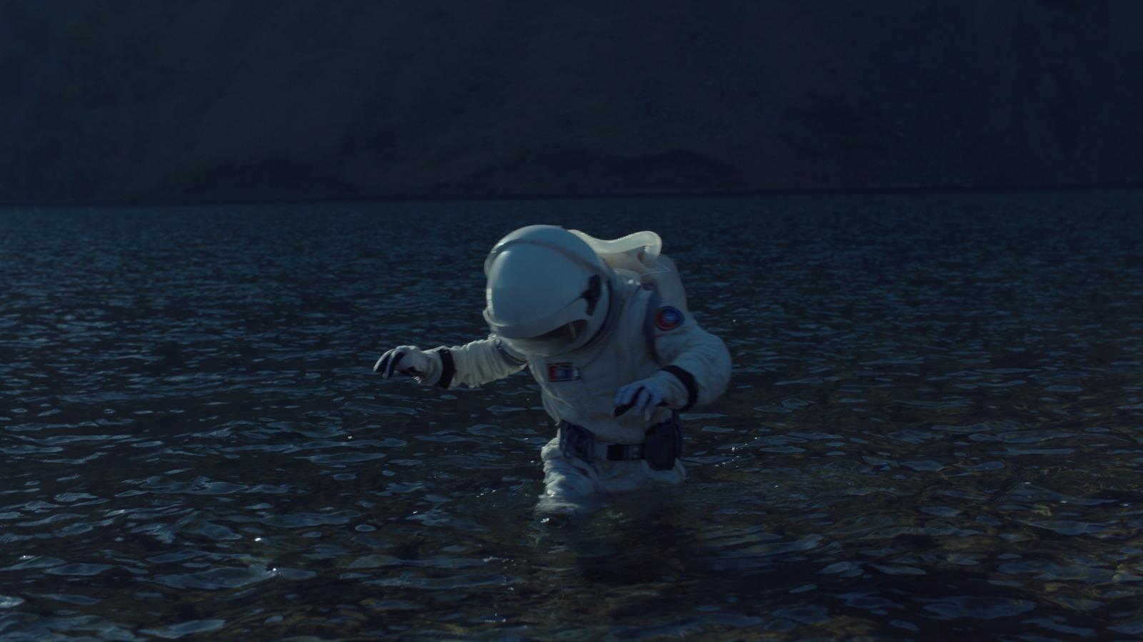 a man in a space suit wading in a body of water