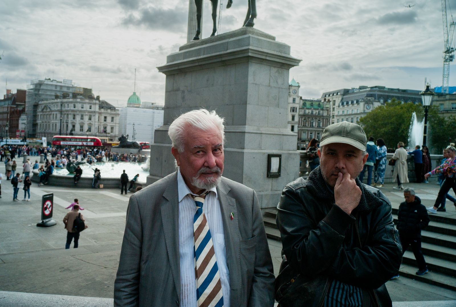 two men standing next to each other in front of a statue