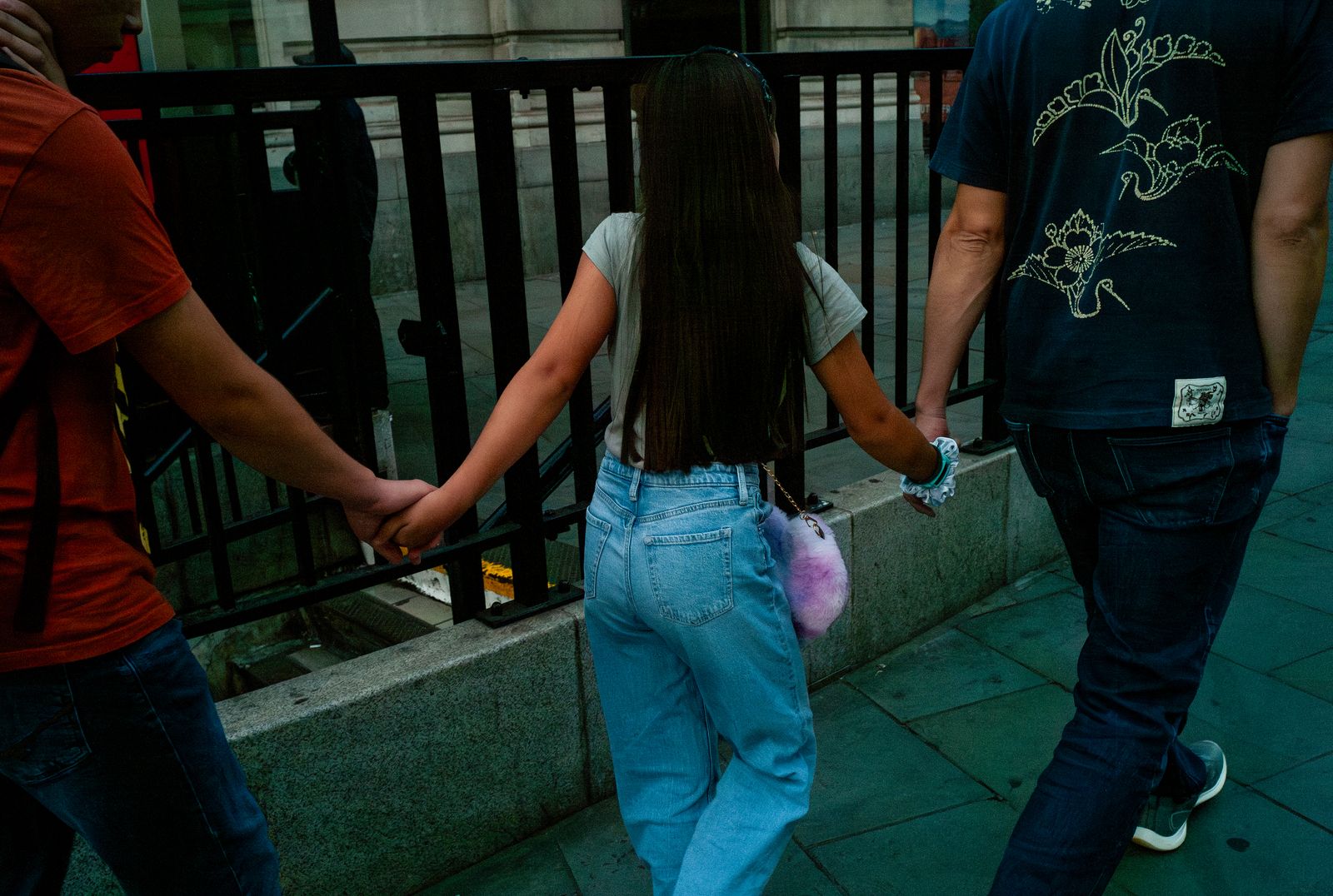 a man and a woman walking down a sidewalk holding hands