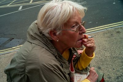 an older woman smoking a cigarette on the street