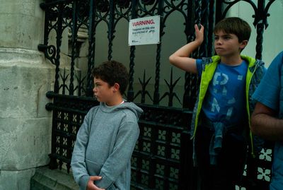 a young boy standing in front of a gate