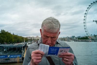 a man is looking at a ticket with a ferris wheel in the background