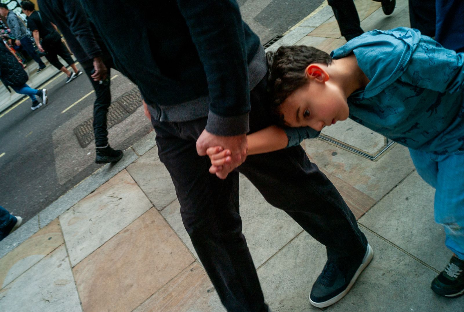 a young boy holding the hand of an older man