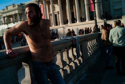 a shirtless man leaning on a railing in front of a building