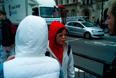 a woman in a red hoodie standing next to a man in a white jacket