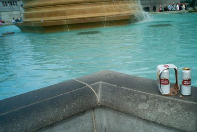 two cans of beer sitting next to a fountain