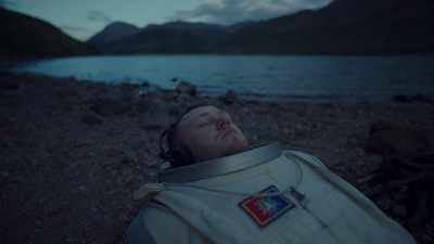 a man laying on the ground next to a body of water