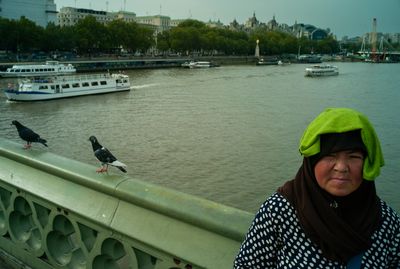 a woman standing on a bridge next to a river