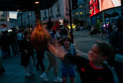 a group of people walking down a street next to a tall building