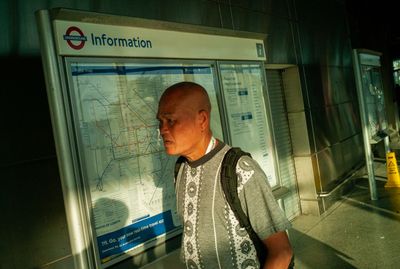 a man standing in front of a subway sign