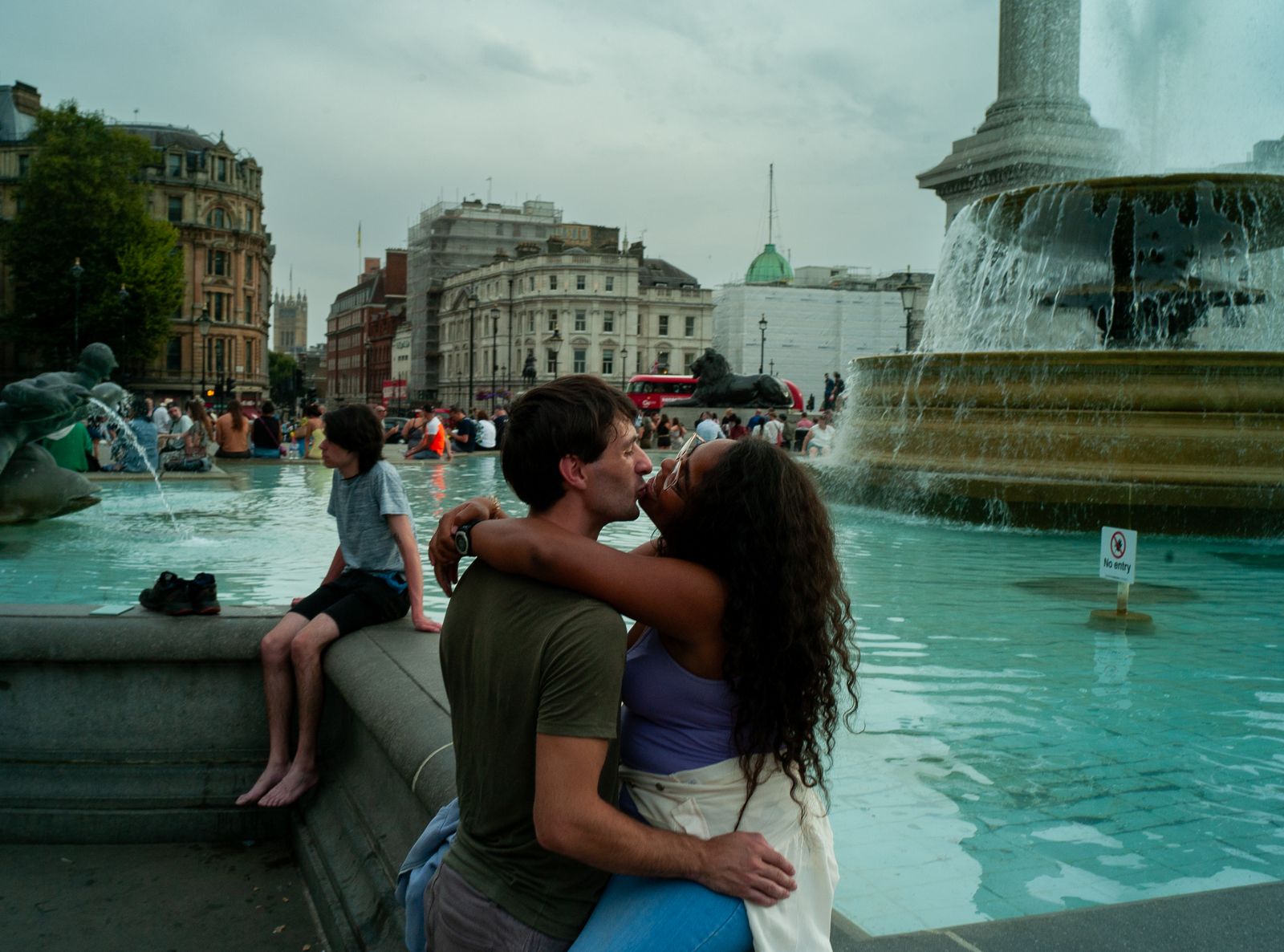 a man and a woman kissing in front of a fountain