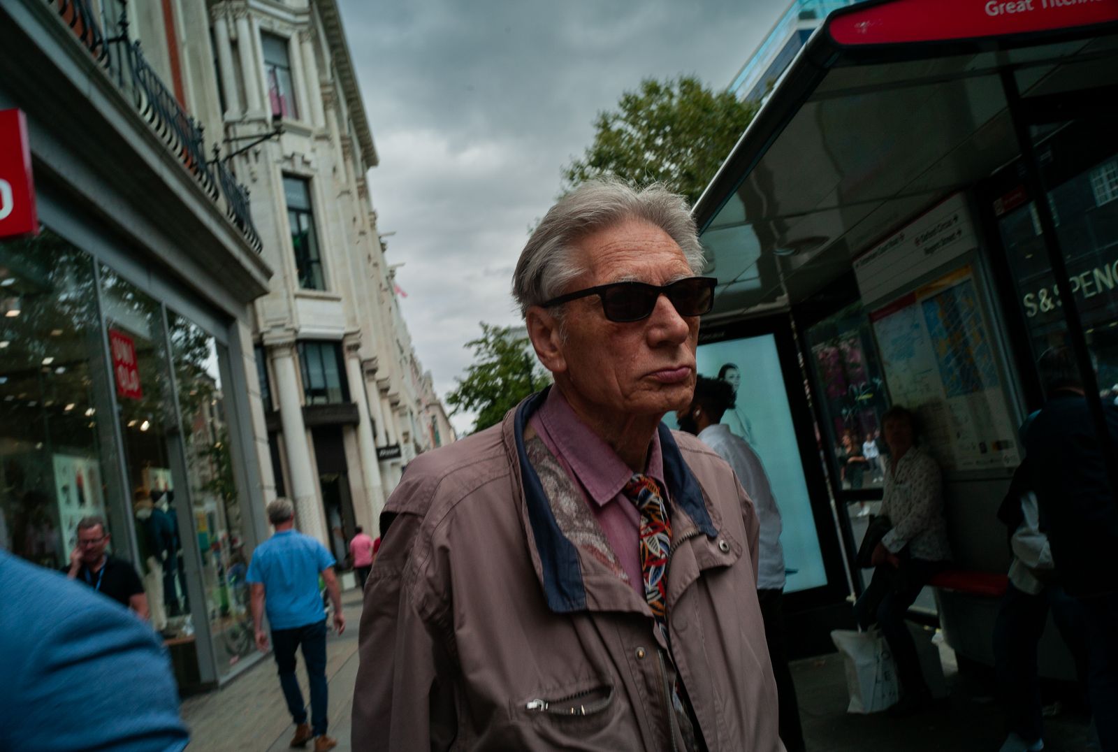 a man in a jacket and tie walking down a street