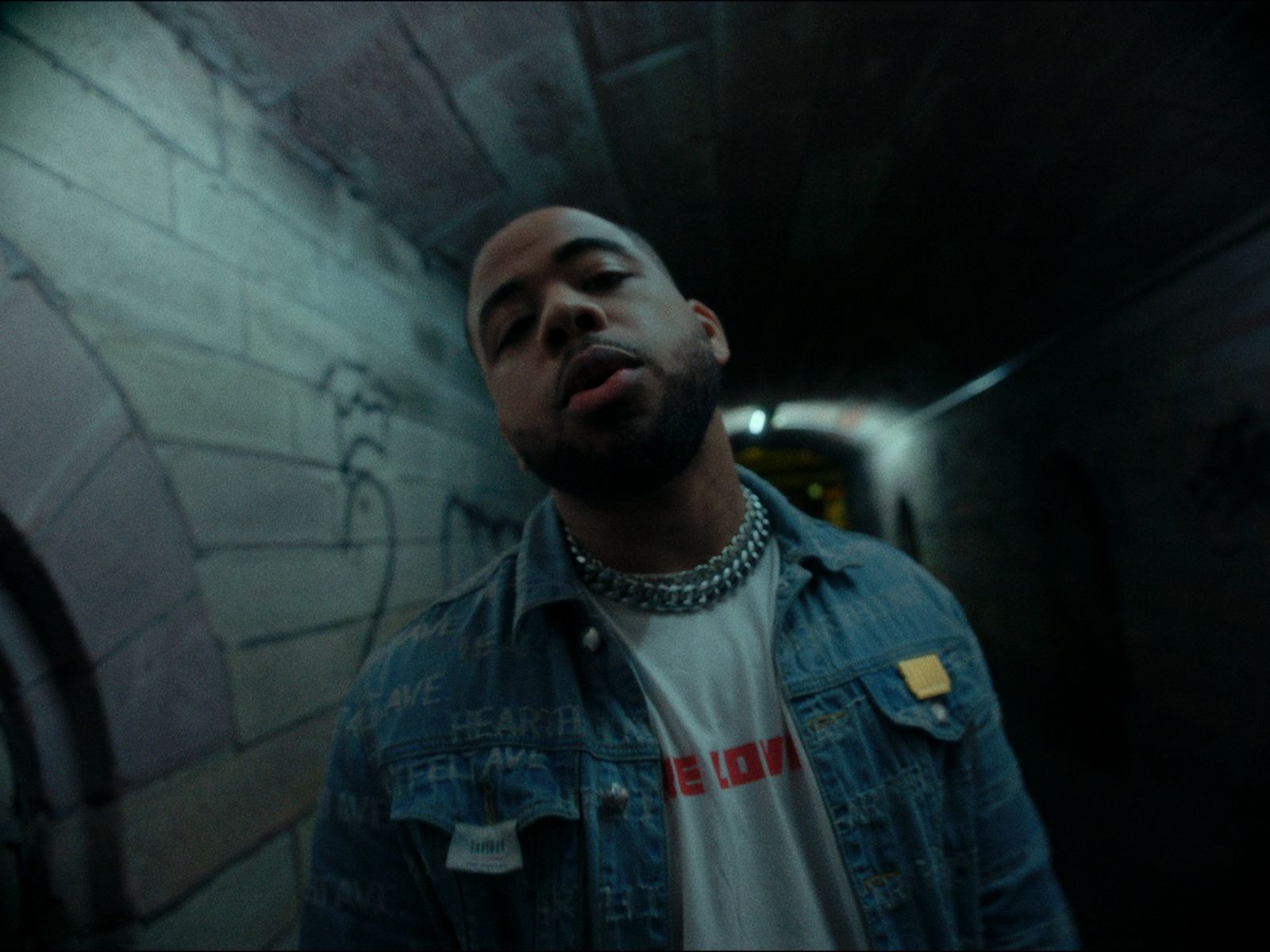 a man in a denim jacket standing in a tunnel