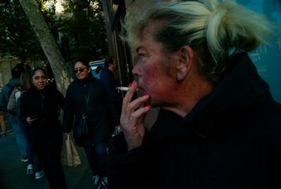 a woman smoking a cigarette on a city street