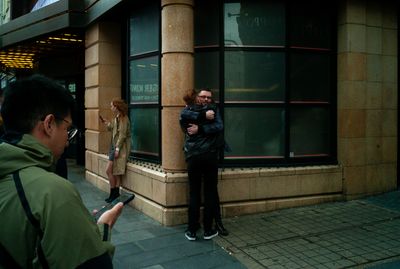 a man taking a picture of a woman in front of a building