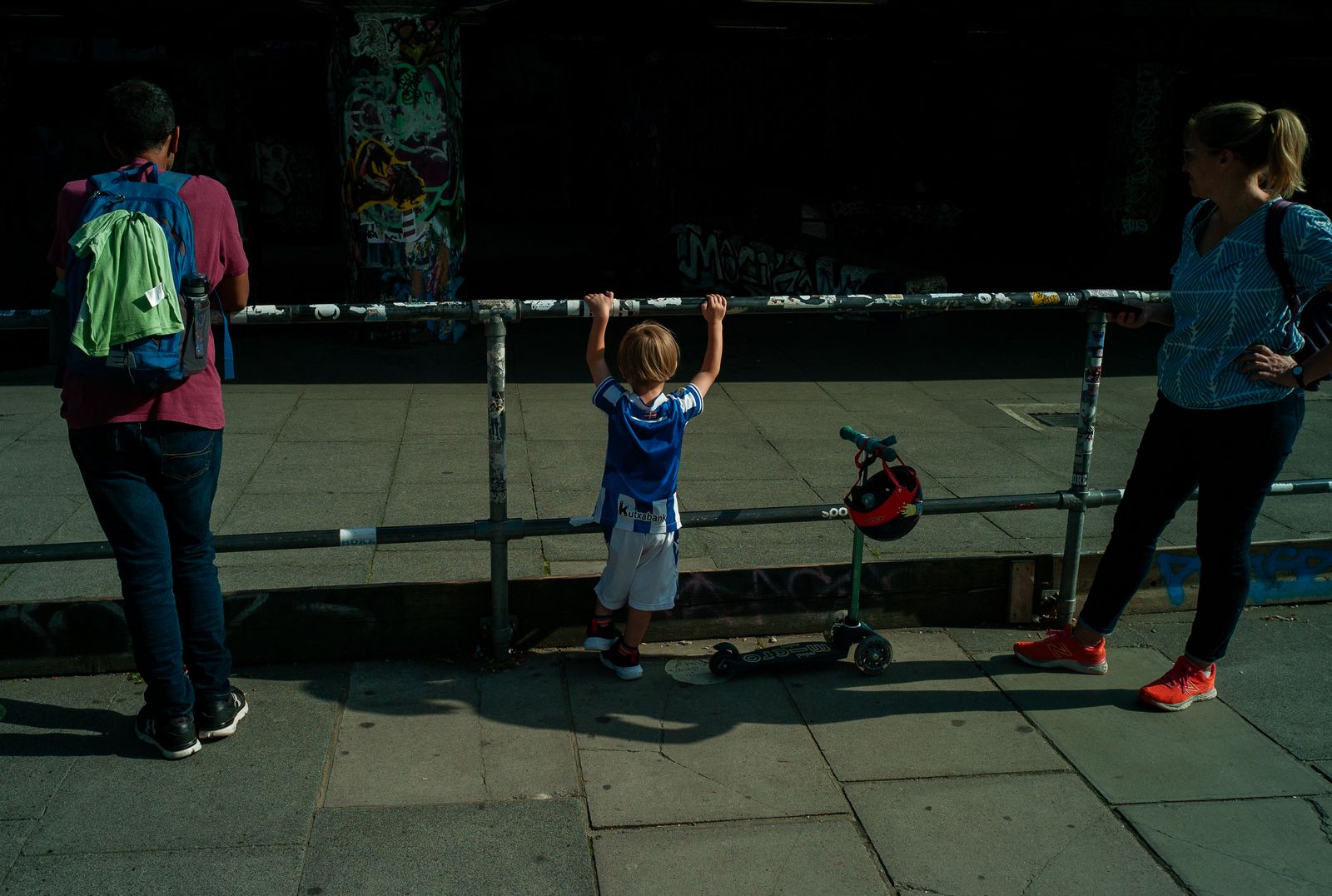 a little boy standing on a skateboard in front of a fence