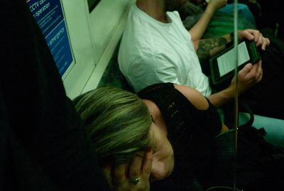 a woman sleeping on a train next to a man