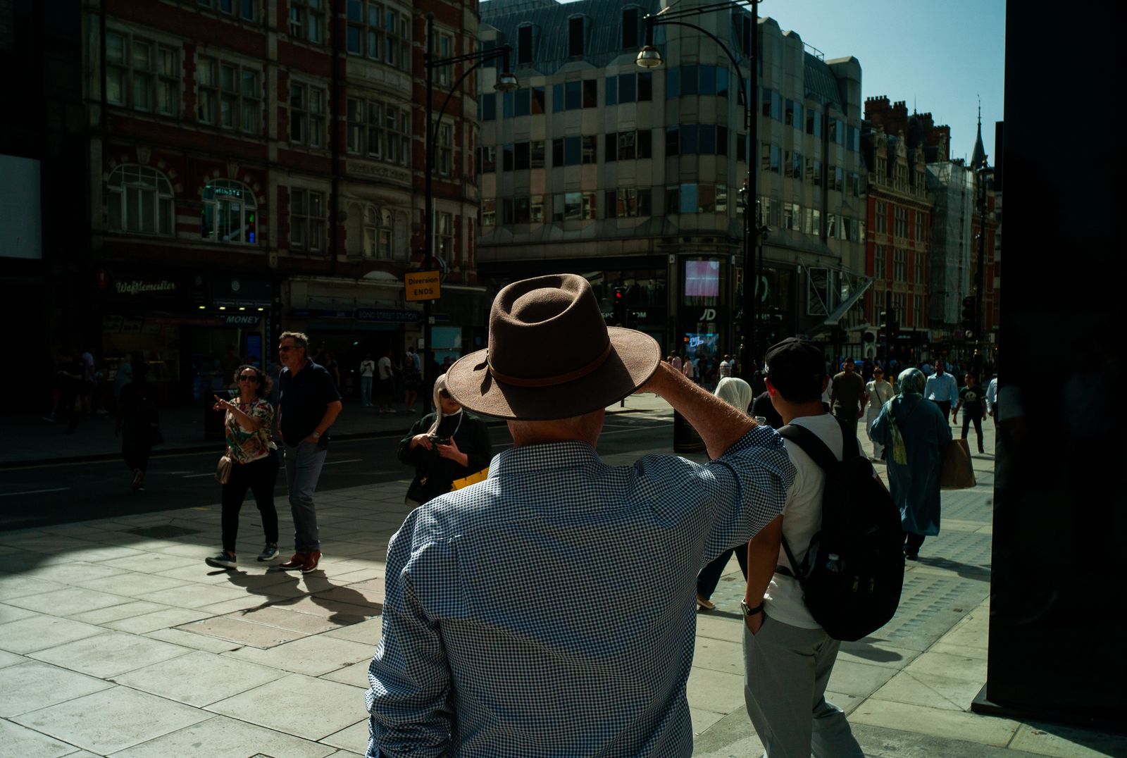 a man wearing a hat standing on a sidewalk