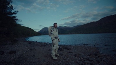 a man in a space suit standing on a rocky shore