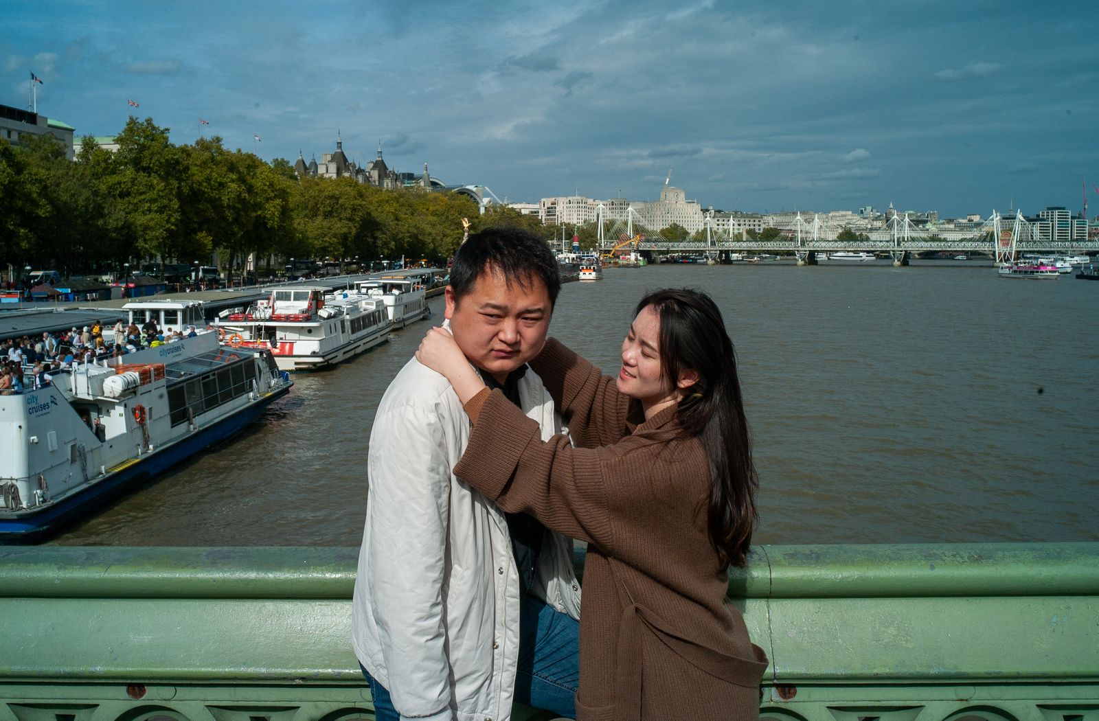 a man and woman standing next to each other near a river