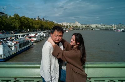 a man and woman standing next to each other near a river