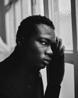 a black and white photo of a person leaning against a window