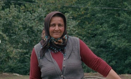 a woman in a red shirt and a gray vest