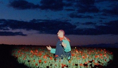 a woman standing in a field of flowers at night