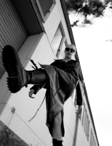 a man in a jacket and sunglasses standing outside of a building